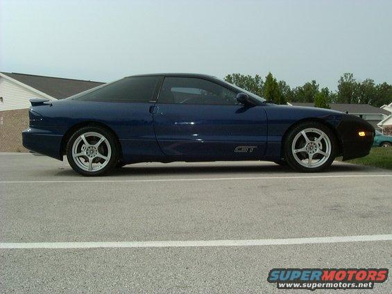 blue 1995 Ford Probe GT parked on asphalt, side view. Has aftermarket wheels and a black bra on the front