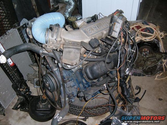 Ford 2.9L V6 engine with blue intake hose, radiator, and wiring harness