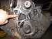 1979 Ford F-150 - Close-up of an engine's timing chain and gears, with a hand pointing to the chain mechanism.