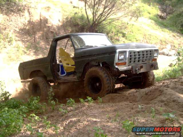 Dark green 1978 Ford Bronco with yellow racing seat, driving off-road