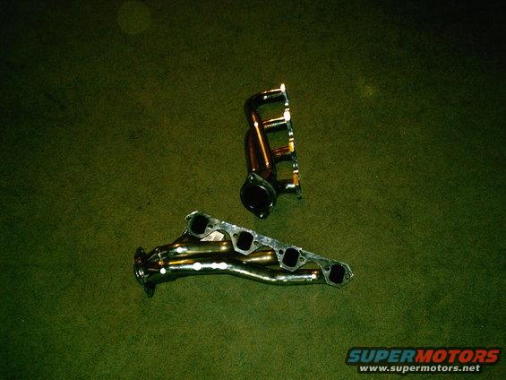 two exhaust manifolds on a green carpet