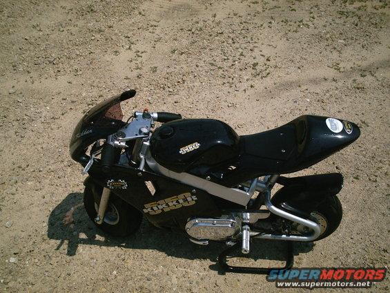 Black mini motorcycle with "KIKKER 550" text on its side fairing, parked on gravel