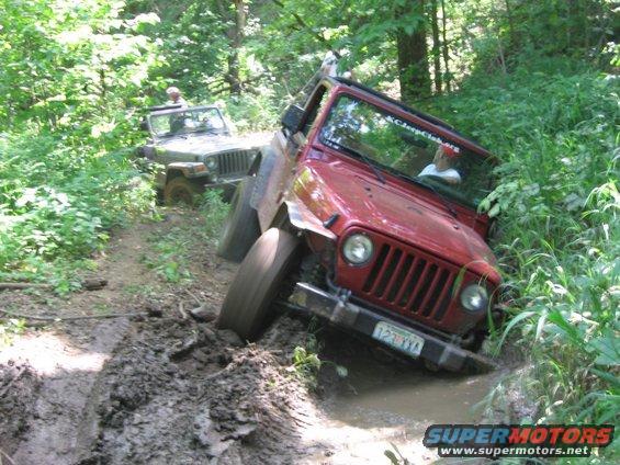 Red Jeep TJ navigating a muddy trail with another Jeep behind it