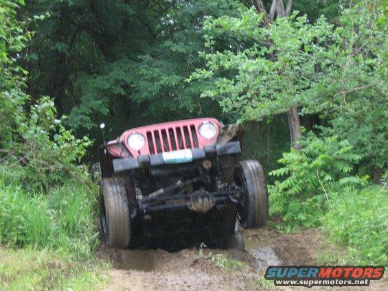 Red 1998 Jeep TJ navigating a muddy off-road trail