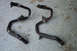 1995 Ford Taurus - Two engine coolant pipes, one black and one rusted, lie on a speckled floor.