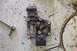 1995 Ford Taurus - A metal engine bracket lies on a garage floor next to a socket wrench, suggesting a repair or replacement in progress.