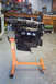 1995 Ford Taurus - Engine on an orange stand in a workshop, showing signs of wear and tear.