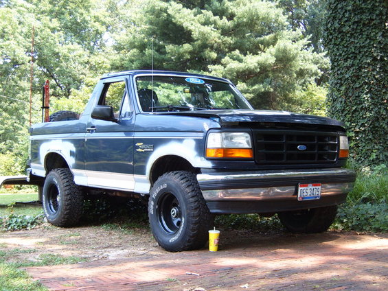 1993 Ford Bronco parked on a brick driveway with trees in the background. License plate DES 3479