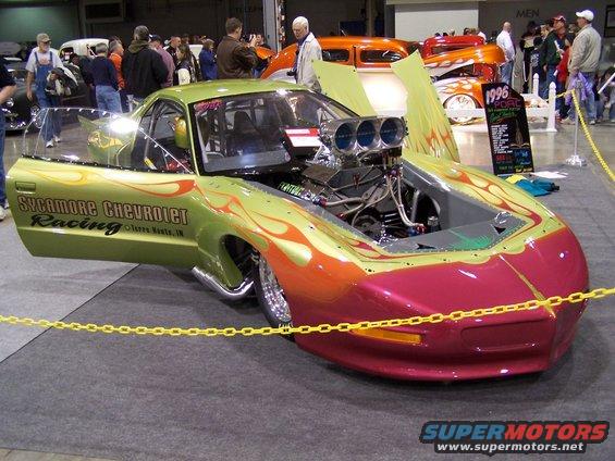 Custom drag car with flames, large engine, and 'Sycamore Chevrolet Racing' text
