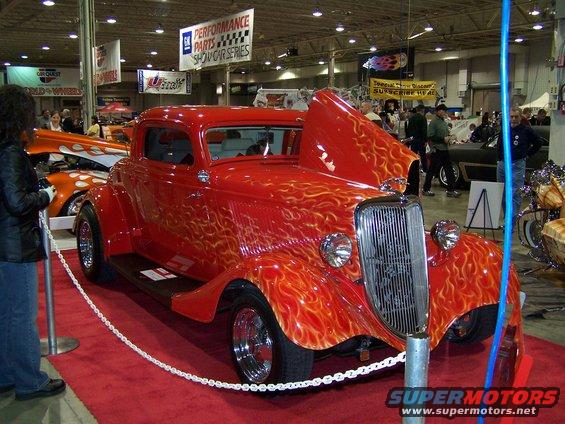 Red hot rod with flame graphics, hood up, on display