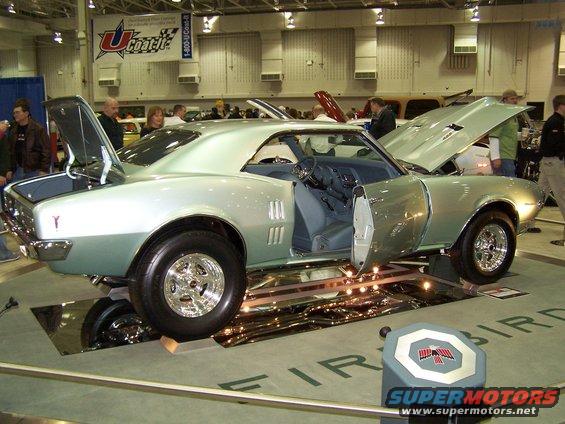 Two-tone light green 1967 Pontiac Firebird coupe with doors and hood open, chrome wheels, blue interior