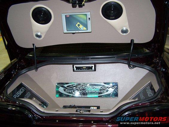 Dark red car trunk interior with two speakers, a screen, a stereo, and custom audio equipment. Fusion and Vanhern Tint & Accessories logos are visible