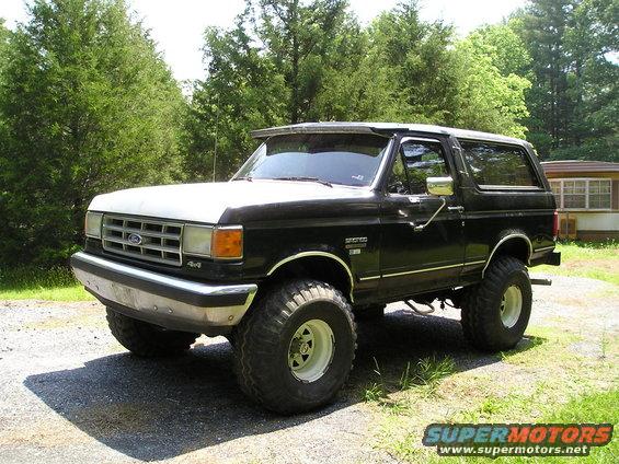 Lifted black Ford Bronco with white top, parked outside