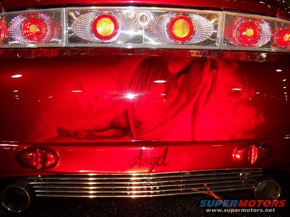 Red car rear bumper with airbrushed angel graphic and chrome grille. Text reads 'Angel'