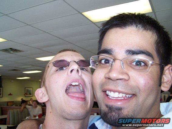 Two men posing for a selfie in a restaurant, one with mouth open and tongue out
