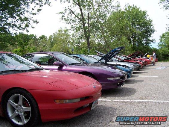 Several Ford Probes parked in a lot, some with hoods up. Red car in foreground