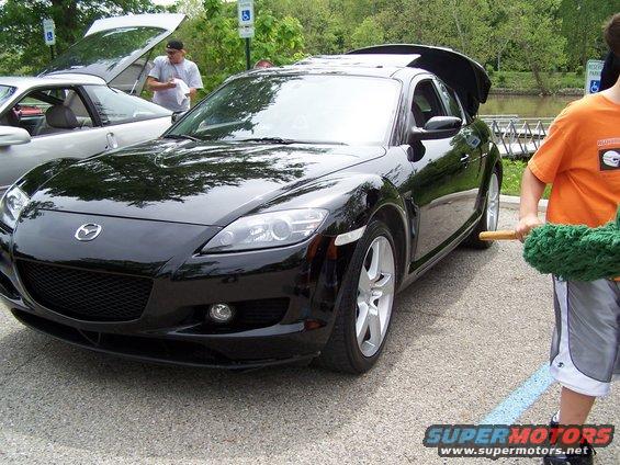 Black Mazda RX-8 with trunk open, parked next to a silver car with hood open