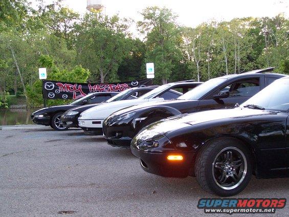 Front view of black Mazda Miata with other Mazdas behind it