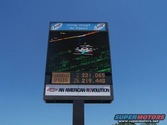 Digital billboard showing racing stats and a helicopter graphic. It has 'Secret' deodorant ads and a Chevrolet logo
