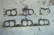 1995 Ford Taurus - Several engine intake manifold gaskets are laid out on a speckled concrete floor, showing their dual-port design.