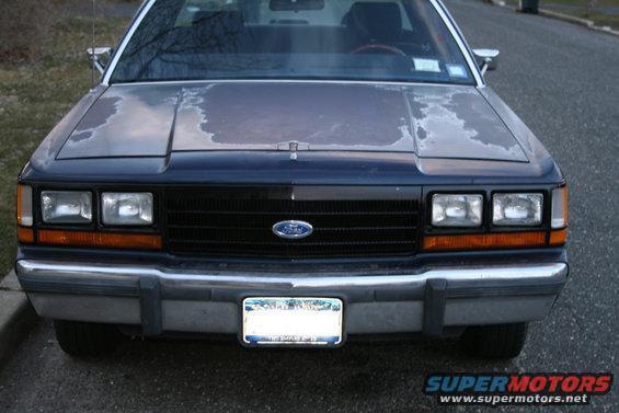 Front view of a dark blue Ford Crown Victoria with peeling paint on the hood