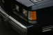 1989 Ford Crown Victoria LTD - Close-up of the front corner of a dark sedan, highlighting the headlight assembly and chrome bumper details.