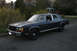 1989 Ford Crown Victoria LTD - A dark blue sedan is parked on a street with houses and trees in the background.