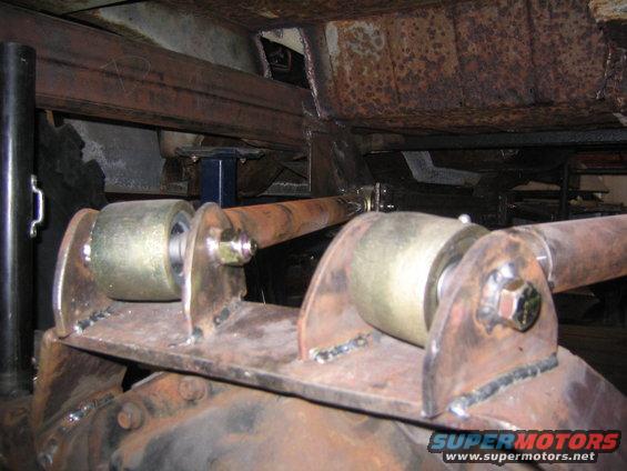 Rear axle with custom suspension links and bushings, showing rust and metal fabrication