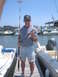 1979 Ford F-250 - A man proudly displays his catch while standing on a dock surrounded by boats.