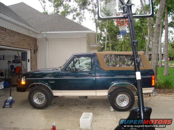 1992 Ford Bronco side view, dark green with tan soft top