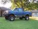 1988 Ford Pickup - This lifted blue Ford F-150 pickup truck is parked on a grassy lawn in front of a residential house.