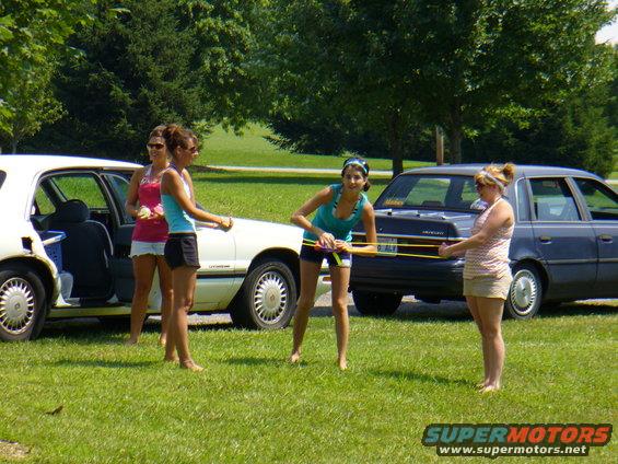 White sedan with open door and dark blue sedan parked on grass