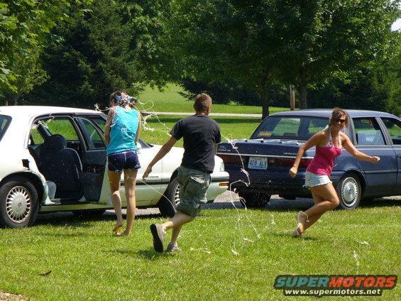 Two cars with people running and streamers flying
