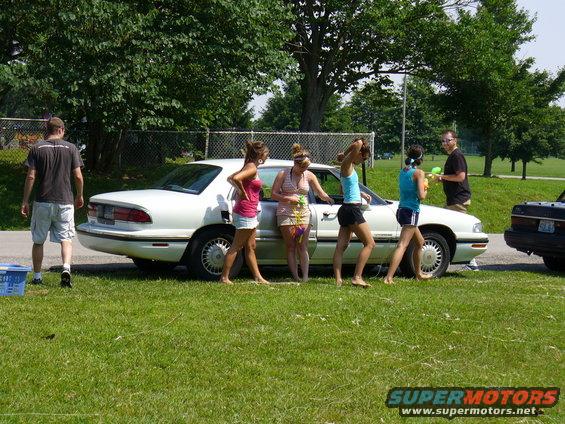 White sedan parked on grass, side view