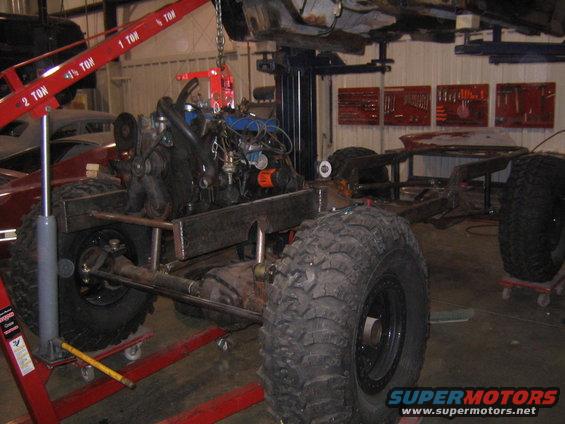 Engine and chassis assembly on red jack stands, large off-road tires