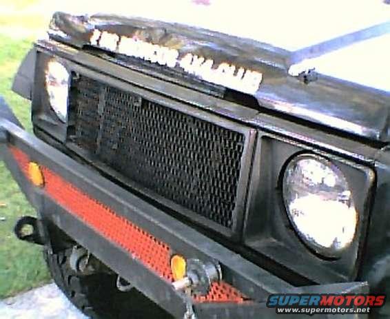 Front grille and bumper of a dark-colored Suzuki Samurai with text on the hood