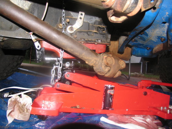 Driveshaft and transmission assembly being supported by a red jack, with chains attached