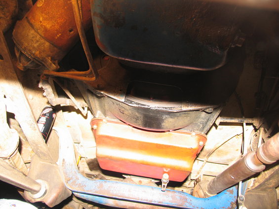 Underside view of a vehicle's transmission pan, starter motor, and driveshaft