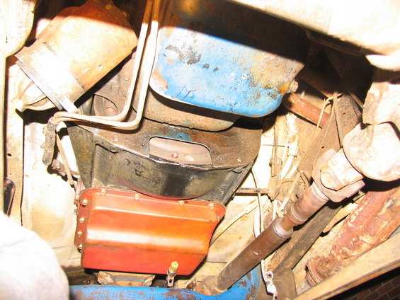 Underside view of a vehicle's transmission pan, driveshaft, and exhaust pipe