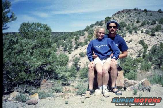 Couple sitting on rocks with a hilly, wooded background