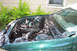 1995 Ford Taurus - The engine bay of a green vehicle is shown with various components and wiring. The vehicle's year is not identifiable from the image.