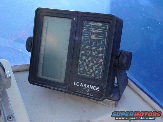 Lowrance X-3 fishfinder with keypad and screen, mounted on a wooden block