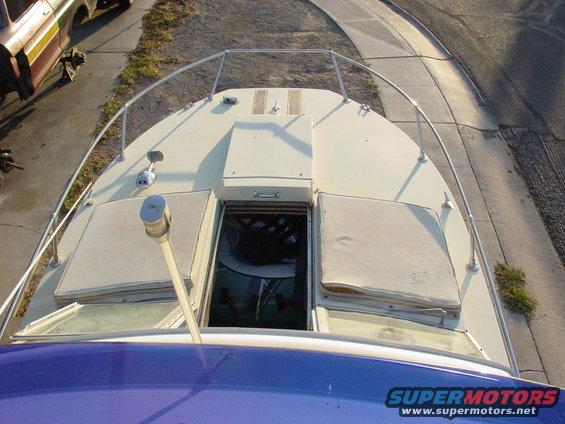 Top view of a boat's deck with a hatch open to the cabin below. A car is visible on the left
