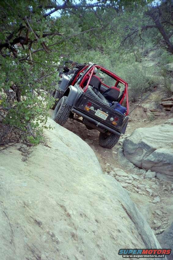 Black off-road vehicle with red roll cage on rocky terrain