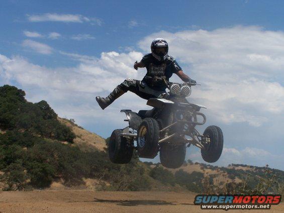 Guy on a quad bike mid-air jump, wearing helmet and protective gear