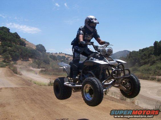 Four-wheeler mid-air jump, front view. Black and silver