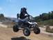 1999 Yamaha WARRIOR - ATV rider catches air on a dirt track with a scenic background.