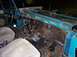 1972 Ford Bronco - The interior of a teal vehicle shows exposed wiring and two grey seats.