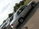 2003 Ford Crown Victoria - Several silver sedans are parked in a row next to a body of water on a sunny day.