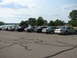 2003 Ford Crown Victoria - Several Ford Crown Victorias are parked in a lot near a body of water under a cloudy sky.